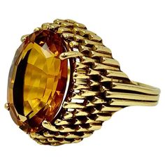 Streamlined, sophisticated Art Deco period 18K gold City Skyline statement ring featuring a superb vivid golden orange oval facet cut citrine of excellent color and clarity. The substantial 18K yellow gold setting is a stylized city skyline composed of gold skyscrapers topped by the citrine gemstone. Historically, citrines have been revered since ancient times as talismans which could manifest desires, especially prosperity. The gemstone was used by the ancient Greeks and Romans in intaglio carv Luxury Faceted Oval Topaz Ring, Luxury Oval Faceted Topaz Ring, Gold Oval Topaz Ring In Art Deco Style, Formal Oval Yellow Gold Topaz Ring, Oval Yellow Gold Topaz Ring For Formal Occasions, Orange Sapphire Ring, Art Deco City, Gold City, Sophisticated Art