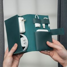 a person holding an electronic device in a green case with cords and plugs attached to it