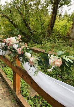 flowers and greenery are arranged on a wooden rail at the end of a path