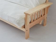 a wooden bed frame with white sheets and pillows