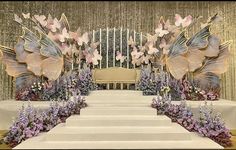 an elaborately decorated stage with flowers and butterflies on the steps leading up to it