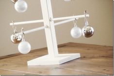 a white and silver christmas tree with ornaments hanging from it's sides on a wooden table