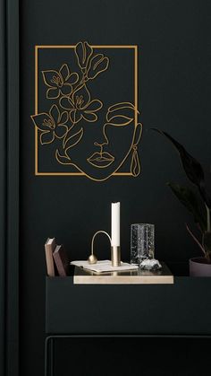 a black wall with a gold frame on it and a plant in front of it