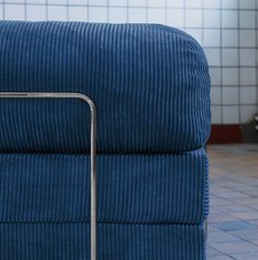 a blue couch with a metal frame on the back and seat, in front of a tiled floor