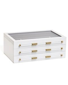 a white box with gold handles and drawers on the bottom is shown in front of a white background