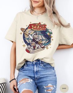 a woman in ripped jeans and a t - shirt with an image of space mountain on it