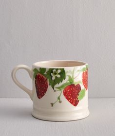 a white cup with strawberries painted on it