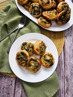 two plates filled with mini spinach pies on top of a wooden table