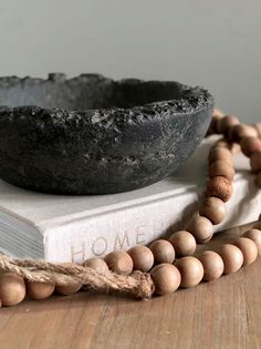 a wooden beaded necklace with a book and bowl on the table next to it