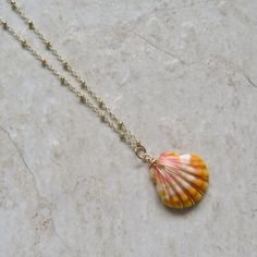 "Hawaiian Sunrise Shell Necklace~ This necklace has a beautiful orange and pink wire wrapped Hawaiian sunrise shell on 14k gold fill satellite chain. Sunrise shells are only found in Hawaii, a true gem to the islands and collectors. Shell approx. 1\" Chain is adjustable 17-18\" Model wearing similar necklace Checkout our sunrise shell jewelry~ https://www.etsy.com/shop/HanaMauiCreations?ref=seller-platform-mcnav&search_query=sunrise+shell+jewelry SHOP~ http://www.etsy.com/shop/HanaMauiCreati Summer Gift Pink Shell Necklace, Gold Shell Necklaces For Beach, Handmade Yellow Gold Necklaces For The Beach, Gold Shell Necklace Beachy Style, Handmade Pink Shell Necklace For Vacation, Gold Wire Wrapped Necklace For The Beach, Handmade Gold Shell Strand Necklace, Handmade Gold Shell With Beachy Style, Wire Wrapped Shell Necklaces