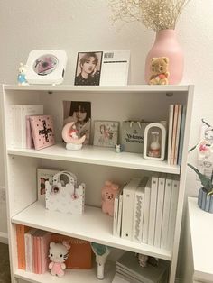 a white book shelf filled with lots of books and other stuff on top of it