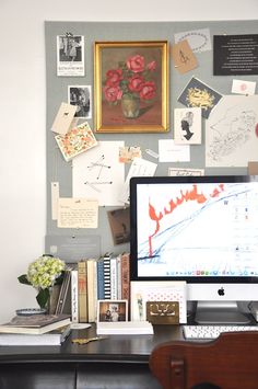 a computer monitor sitting on top of a desk next to a keyboard and mouse in front of a wall covered with pictures