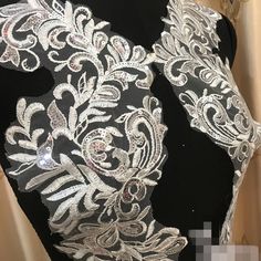 the back of a black and white dress with silver sequins on it's shoulders