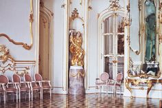 an ornately decorated room with chairs, mirrors and gold trimmings on the walls