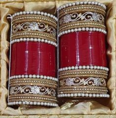 two red and gold bangles in a box with pearls on the rims, sitting next to each other