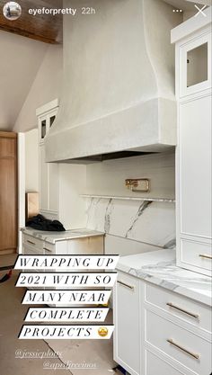 a kitchen with white cabinets and marble counter tops, including an oven hood over the range