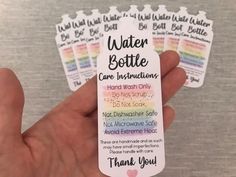 a person holding four water bottle labels in their hand