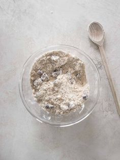 a glass bowl filled with oatmeal and blueberries next to a spoon