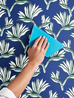 a person is using a blue cloth to clean the wallpaper with a hand on it