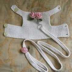 a crocheted baby outfit with pink flowers on the top and two white handles