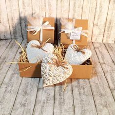 four heart shaped boxes with ribbons and tags on them sitting on a wooden floor next to each other