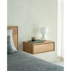 a bedroom with a bed, nightstand and lamp on top of the night stand next to the window