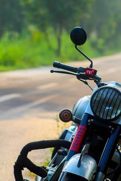 a close up of a motorcycle parked on the side of a road with trees in the background