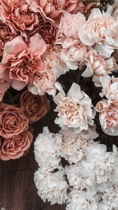 a bunch of pink and white flowers sitting on top of a wooden table next to each other