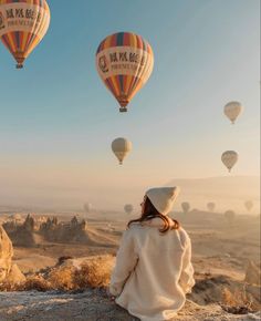 a woman looking at hot air balloons in the sky