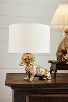 a dog figurine sitting on top of a wooden table next to a lamp