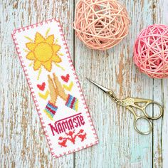 a pair of scissors and some yarn on a wooden table with two balls of yarn