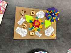 a paper bag with flowers and letters on it sitting next to other items that include scissors