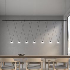 a long table with chairs and lights hanging from it's sides in an empty room