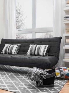 a living room with a couch, rug and window in it's center area