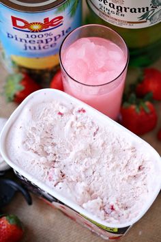 strawberry ice cream in a bowl next to two jars of yogurt and strawberries