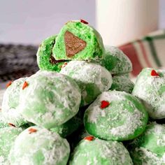 a pile of green and red cookies sitting on top of each other next to a white cup