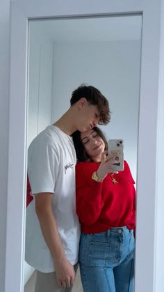 a man and woman standing in front of a mirror taking a selfie with their cell phone