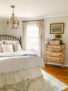 a bed sitting in a bedroom next to a window with curtains on it's sides