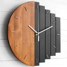 a clock made out of wood and metal on the side of a white wall with wooden slats