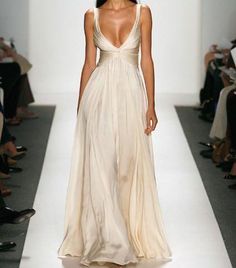 a woman walking down a runway in a white dress