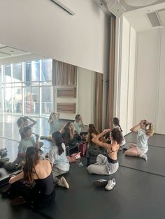 a group of women sitting on the floor in front of a mirror with their backs turned