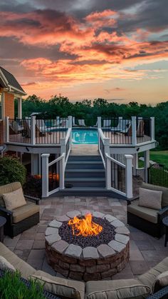 a fire pit sitting in the middle of a patio next to a swimming pool at sunset