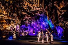 three people standing in front of an illuminated cave