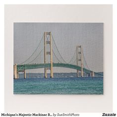 a photo of a bridge in the ocean with blue water and gray sky behind it