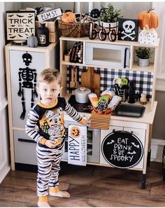 a little boy standing in front of a halloween themed play kitchen with lots of decorations