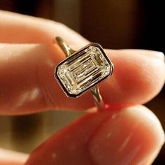 a close up of a person holding a ring with a diamond in it's middle