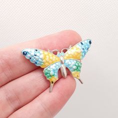 a small butterfly brooch sitting on someone's hand