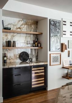 a kitchen with marble counter tops and wooden shelves on the wall next to a wine rack