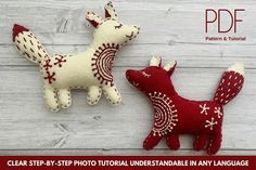 two red and white stuffed animals sitting next to each other on a wooden surface,