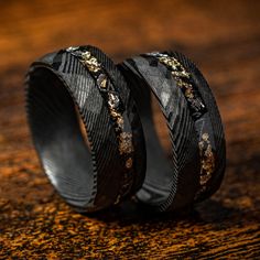 two black wedding bands with gold flecks on them